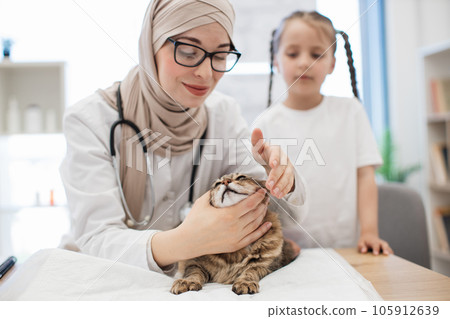 Animal doctor testing cat's eyes with tween guardian behind Animal doctor testing cat's eyes with tween guardian behind 105912639