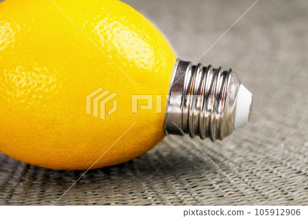 Creative lemon light bulb with a shiny metal threaded base. Conceptual energy idea. Creative lemon light bulb with a shiny metal threaded base. Conceptual energy idea. 105912906