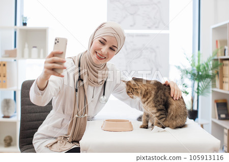 Muslim lady taking selfie of animal patient at vet visit 105913116
