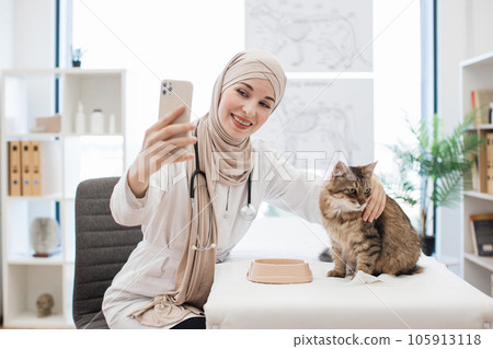Muslim lady taking selfie of animal patient at vet visit Muslim lady taking selfie of animal patient at vet visit 105913118