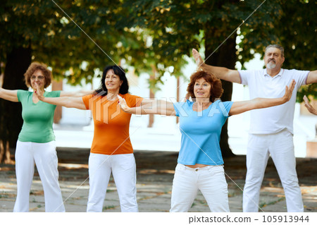 Warming up exercises. Group of elderly people, man and women training outdoors, doing healthy workout in park 105913944
