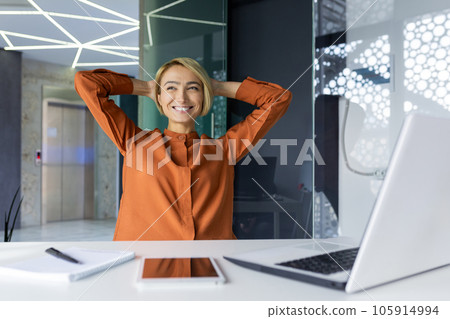 Dreamy thinking woman completed work well, successful achievement result resting and smiling at workplace sitting using laptop, hands behind head relaxing. Dreamy thinking woman completed work well, successful achievement result resting and smiling at workplace sitting using laptop, hands behind head relaxing. 105914994