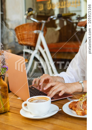An independent worker sits with a laptop in a summer playground cafe An independent worker sits with a laptop in a summer playground cafe 105915166