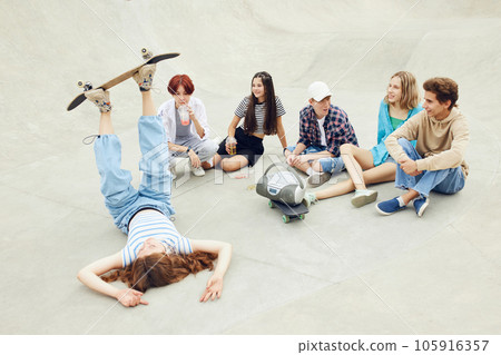 Friends meeting on skaet park, outdoors, skateboarding, training, having fun and talking. Summer activity 105916357