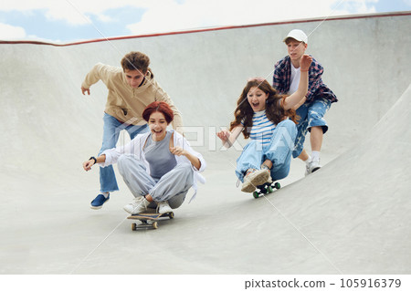 Group of cheerful friends, teens spending good time together on skatepark, skateboarding, laughing. Joy 105916379