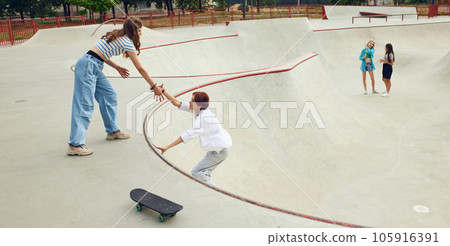 Cheerful friends, teens attending skatepark, skateboarding, training having fun together. Leisure time Cheerful friends, teens attending skatepark, skateboarding, training having fun together. Leisure time 105916391