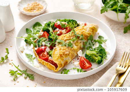 Omelette stuffed with tomato, broccoli feta cheese and fresh green salad. Healthy diet food for breakfast Omelette stuffed with tomato, broccoli feta cheese and fresh green salad. Healthy diet food for breakfast 105917609