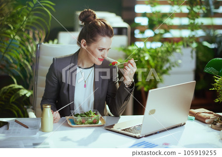 modern accountant woman in modern green office eating salad 105919255
