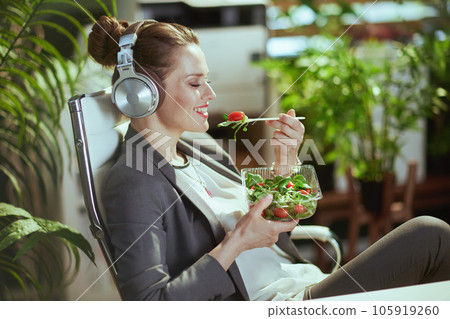 business owner woman eating salad and listening to music business owner woman eating salad and listening to music 105919260