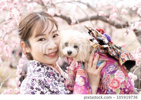 A woman who smiles while holding a dog in full bloom A woman who smiles while holding a dog in full bloom 105919736