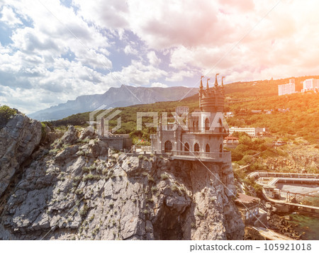 Crimea Swallow's Nest Castle on the rock over the Black Sea. It is a tourist attraction of Crimea. Amazing aerial view of the Crimea coast with the castle above abyss on sunny day. Crimea Swallow's Nest Castle on the rock over the Black Sea. It is a tourist attraction of Crimea. Amazing aerial view of the Crimea coast with the castle above abyss on sunny day. 105921018