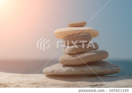 Pyramid stones on the seashore on a sunny day on the blue sea background. Happy holidays. Pebble beach, calm sea, travel destination. Concept of happy vacation on the sea, meditation, spa, calmness. Pyramid stones on the seashore on a sunny day on the blue sea background. Happy holidays. Pebble beach, calm sea, travel destination. Concept of happy vacation on the sea, meditation, spa, calmness. 105921185