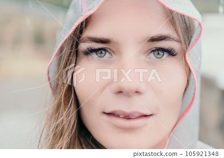 Woman rain umbrella. Happy woman portrait wearing a raincoat with transparent umbrella outdoors on rainy day in park near sea. Girl on the nature on rainy overcast day. Woman rain umbrella. Happy woman portrait wearing a raincoat with transparent umbrella outdoors on rainy day in park near sea. Girl on the nature on rainy overcast day. 105921348