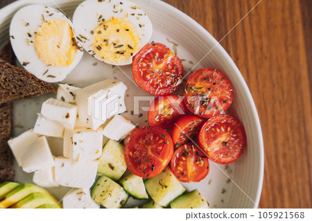 Vegetable salad with cheese and eggs and rye bread on a white plate 105921568