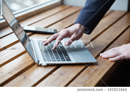 Businessperson with watch on wrist working on laptop, fingers typing. Close up on table 105921668
