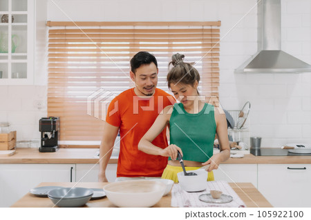 Husband looking at wife who cooking lunch for him. Happy couple in kitchen. Husband looking at wife who cooking lunch for him. Happy couple in kitchen. 105922100