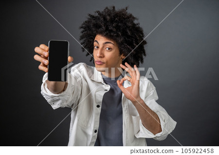 Curly-haired young man with a smartphone in hand 105922458