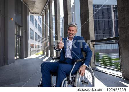 Disabled man wearing official style suit in wheelchair showing thumb up like gesture. Disabled man wearing official style suit in wheelchair showing thumb up like gesture. 105922539