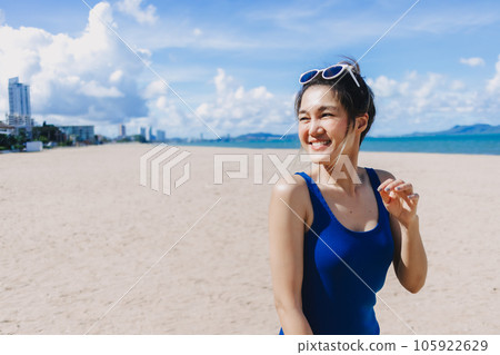 Happy smile woman in blue dress walking on the sunny beach of Pattaya. 105922629