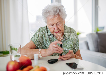 Diabetic senior patient checking her blood sugar level with fingerstick testing glucose meter. 105922941