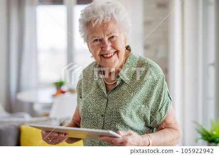 Portrait of beautiful senior lady with tablet in hands at home. 105922942