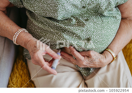 Diabetic senior patient injecting insulin in her belly. 105922954