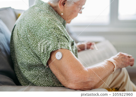 Diabetic senior patient using continuous glucose monitor to check blood sugar level at home. Diabetic senior patient using continuous glucose monitor to check blood sugar level at home. 105922960