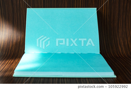 An open turquoise notebook for writing lies on a wooden background 105922992