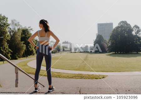 Rear view of young woman runner in the city park in the early morning. Rear view of young woman runner in the city park in the early morning. 105923096