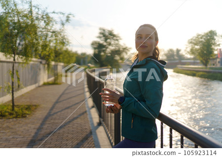 Sporty woman drinking water from bottle after workout session. 105923114