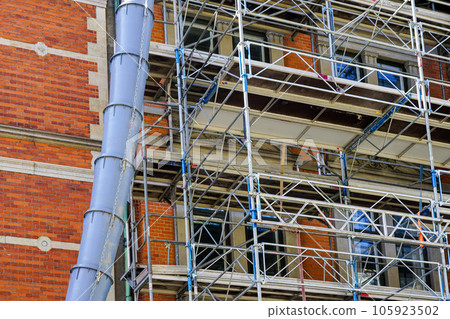 Blue plastic construction debris pipe and scaffolding at building renovation construction site Blue plastic construction debris pipe and scaffolding at building renovation construction site 105923502