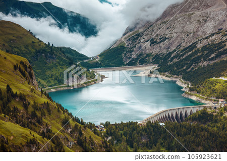 landscape with mountains, hills, Fedaia lake, trees and fog 105923621