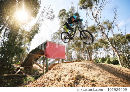 Bike, jump and man with ramp, outdoor and speed for sports, race or adventure in summer, woods or nature. Extreme cycling, person and training on trail, competition or challenge for fitness in forest 105924409
