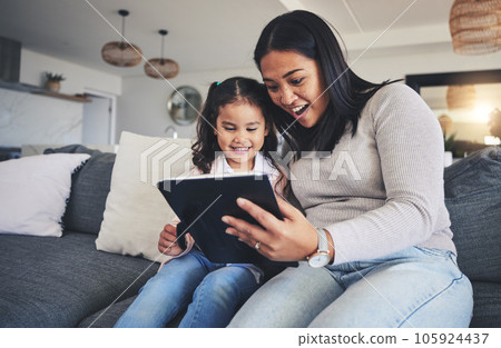 Tablet, surprise and a mother on the sofa with her daughter in the living room of their home together. Wow, family or children with a mother and girl looking at social media or a good news email 105924437
