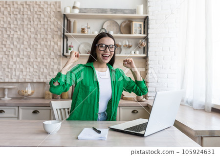 Portrait of a young business woman, a freelancer who rejoices at the finished successful project, looks at the camera and rejoices at the success. 105924631