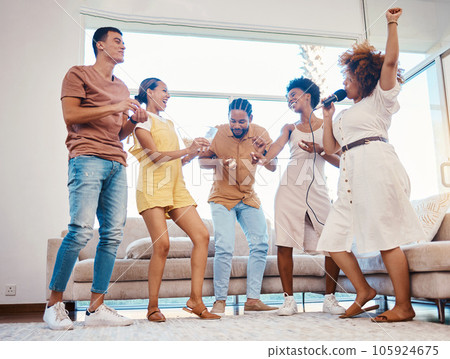 Karaoke, party and friends dancing in the living room with a microphone to music, playlist or radio. Happy, diversity and young people singing, moving and having fun together for bonding at home. 105924675