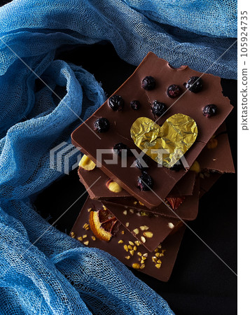 Pieces of chocolate with golden foil heart. With berries, strawberries, oranges Pieces of chocolate with golden foil heart. With berries, strawberries, oranges 105924735