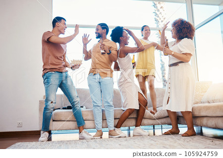 Friends, excited and beer to celebrate at a house with happiness, fun and a high five in a lounge. Diversity, alcohol and party with men and women together for drinks, gathering or reunion at home 105924759