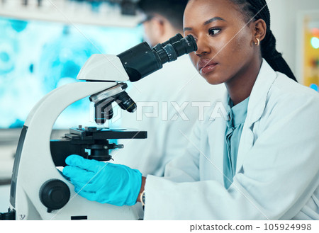 Microscope, scientific and female scientist working in a medical study in pharmaceutical lab. Professional, science and African woman researcher doing chemistry research with biotechnology equipment. 105924998