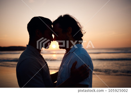 Sunset, embrace and gay men on beach, silhouette and love on summer vacation together in Thailand. Sunshine, ocean and romance, lgbt couple hug in nature and fun holiday with pride, sea and waves. Sunset, embrace and gay men on beach, silhouette and love on summer vacation together in Thailand. Sunshine, ocean and romance, lgbt couple hug in nature and fun holiday with pride, sea and waves. 105925002