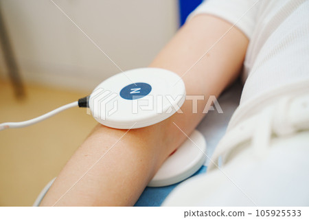 A patient on a magnetotherapy procedure on hand. A patient on a magnetotherapy procedure on hand. 105925533