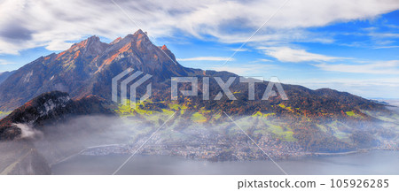 Fabulous autumn view of Stansstad city and Lucerne lake with mountaines and fog. Fabulous autumn view of Stansstad city and Lucerne lake with mountaines and fog. 105926285