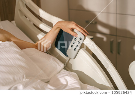 Close up of woman patient hand presses the buttons on the hospital bed 105926424