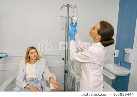 Professional doctor putting an IV drip to female patient intravenously in hospital ward Professional doctor putting an IV drip to female patient intravenously in hospital ward 105926444