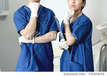 Thinking male and female healthcare workers wearing scrubs Thinking male and female healthcare workers wearing scrubs 105926456