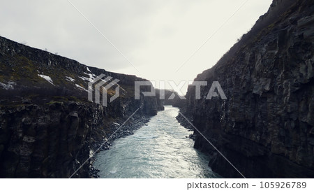 Drone shot of icelandic gullfoss cascade, majestic water stream flowing between rocky hills and cliffs. Beautiful waterfall in iceland running down off mountains, winter landscape. Slow motion. 105926789