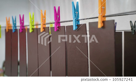 Pieces of genuine leather hanging on clothesline with colorful clothespins for drying after painting 105927241