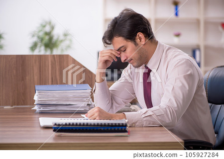 Young male employee and too much work in the office 105927284