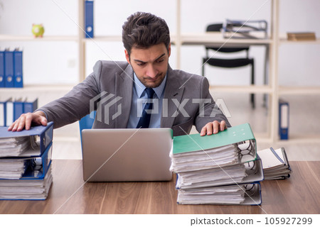 Young male employee and too much work in the office 105927299