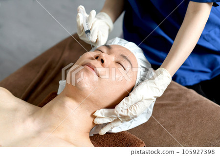 Young man receiving cosmetic injection at plastic surgery Young man receiving cosmetic injection at plastic surgery 105927398